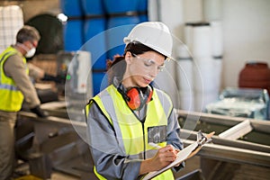 Female technician writing on clipboard