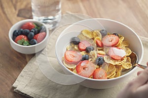 Female teen girl hand eats healthy breakfast with corn flakes and berries