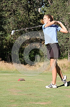 Female teen golfer after swing