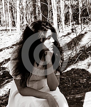 Female teen sitting outside in woods in deep thought