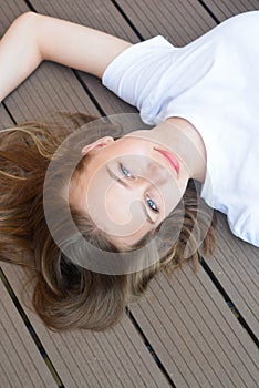 Female teenager smiling, layingon the floor. Summer, portrait of young girl with long, blonde hair