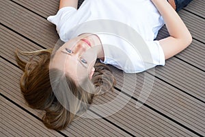 Female teenager smiling, layingon the floor. Summer, portrait of young girl with long, blonde hair