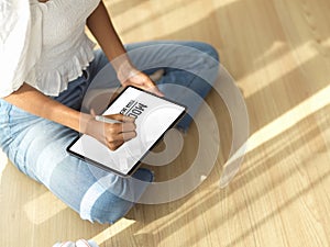 Female teenager using digital tablet on her lap while legs crossed sitting on the floor