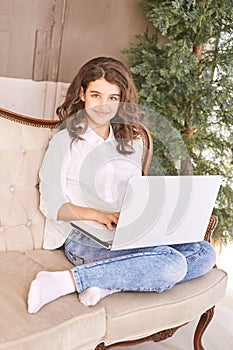 Female teenager using laptop on sofa. School online lessons