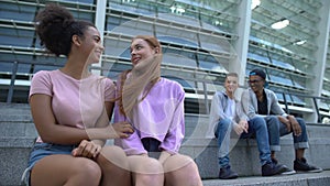 Female teenagers looking at male students sitting stairs, first relations, flirt