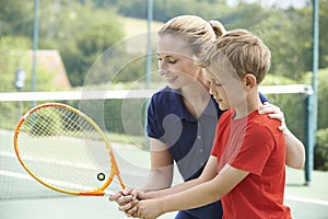 Female Tennis Coach Giving Lesson To Boy