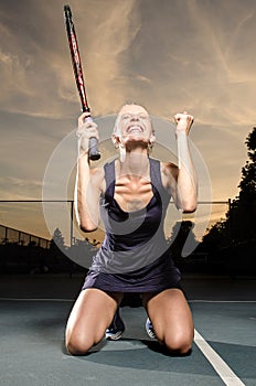 Female tennis player celebrating on knees photo