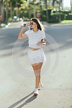 female tennis player drinking water, young