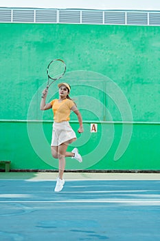 Female tennis player moving in jumping after hitting ball