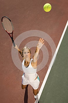 Female Tennis Player Serving Ball On Court