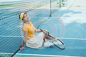 female tennis player sitting in spoiled pose on tennis court