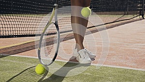 Female tennis player spining racket on the ground and throwing tennis ball.