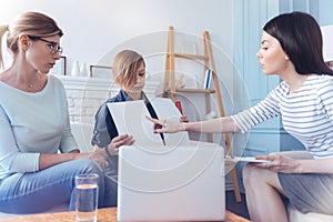 Female therapist and teenage child with mom during psychotherapeutic test