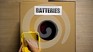 Female throwing used batteries in box for recycling, heavy metals disposing