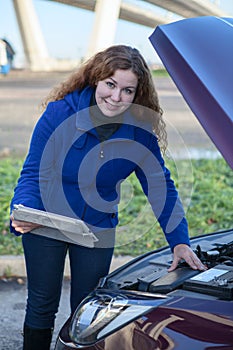 Female with touchpad near car with opened hood