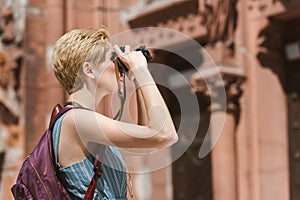 female tourist with backpack taking photo on camera