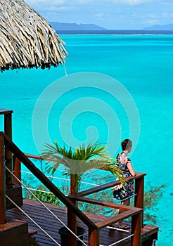 Female tourist on the balcony of an overwater bungalow