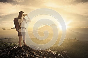 Female tourist with binoculars in the cliff