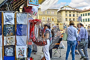 A woman shops for souvenirs from a small shop stand selling leather goods and clothing in Piazza Santa Croce in Florence Italy