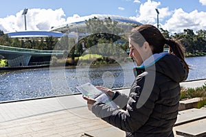 Female tourist looking at a map in front of the Adelaide Oval, next to river Torrens. Sports stadium used for cricket, Australian photo