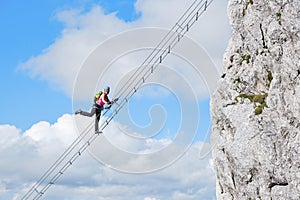 Female tourist raising her leg on via ferrata route called Intersport Klettersteig Donnerkogel, in Austria. Stairway to heaven