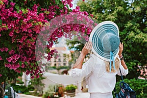 Female tourist smelling beautiful colorful blossom flower in Assos, Kefalonia. Summer travel vacation concept