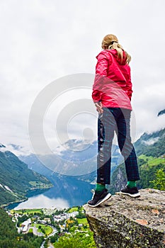 Female tourist standing on the cliff edge near Flydalsjuvet Viewpoint. Travel Norway