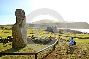 Female tourist taking photo of solitary Moai near the famous 15 Moais on the platform of Ahu Tongariki, Easter Island