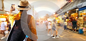 Female tourist traveling backpacker happy and take a photo in outdoor night market