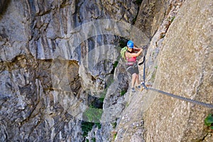 Female tourist traversing a via ferrata section in Turda gorge Cheile Turzii Romania, with impressive rock structure in the back