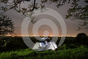 Female tourist using her laptop in the camping at night