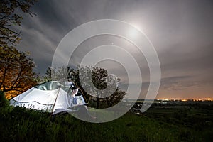 Female tourist using her laptop in the camping at night