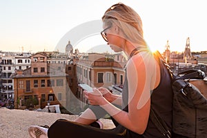 Female tourist using mobile phone travel app close to Piazza di Spagna, landmark square with Spanish steps in Rome