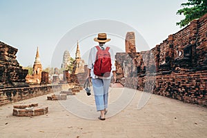 Female tourist walking with compact photo camera through Ayutthaya Wat Phra Ram ancient ruins in Thailand. History, tourism,