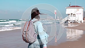 Female tourist walks on summer seashore. Freedom. Wind blowing in hair. European girl on ocean beach. Slow motion.