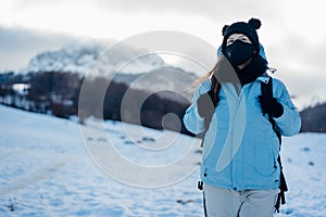 Female tourist wearing a protective mask in nature on mountain holiday vacation.Active vacation during the pandemic.Natural beauty