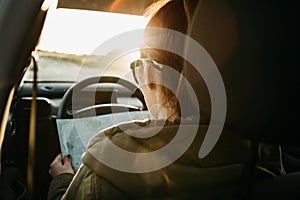 Female tourist or woman driver inside the car who looks at the map for a further trip