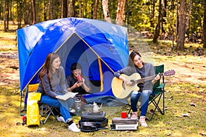 Female tourists camping and playing guitar in the forest