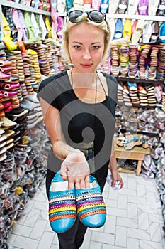 Female tourists looking at traditional arabic colorful leather shoes in shopping stall market in medina while traveling