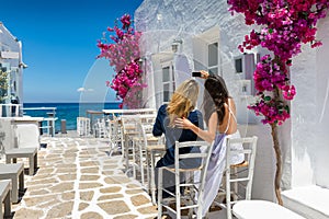 Female tourists are taking a selfie photo in the whitewashed alleys of Naousa village on Paros