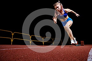 Female track runner bursting off starting block