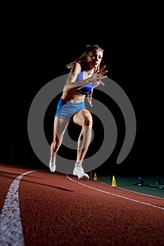 Female track runner bursting off starting block