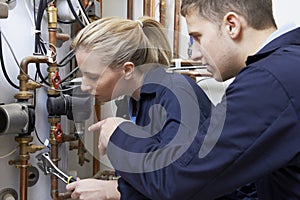 Female Trainee Plumber Working On Central Heating Boiler