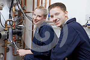 Female Trainee Plumber Working On Central Heating Boiler