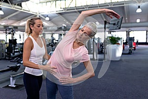 Female trainer assisting active senior woman in modern sports center