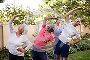 Female trainer guiding senior people while exercising