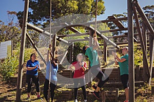 Female trainer instructing women to climb a rope in the boot camp