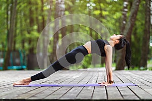 Female trainer in sportswear, practicing yoga asanas, doing the reverse plank