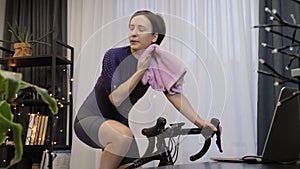 Female is training on indoor cycling trainer. Woman is cycling on stationary bike