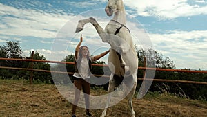 Female trains a horse at a racetrack holding her by the reins.